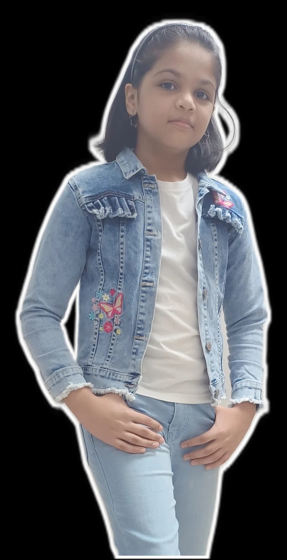 Nitya in a denim jacket with butterfly embroidery, standing with her hands in her pockets